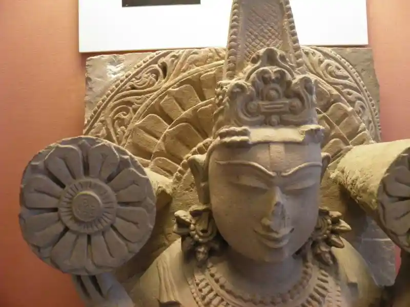 Cross-like symbol on the head of the standing figure of the god Surya carved in a buff-colored sandstone
